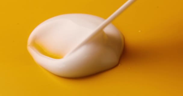 Sample smear of white cream for face, organic cosmetic liquid, cream smudge on yellow background. Motion of the beauty skincare product. - Кадры, видео