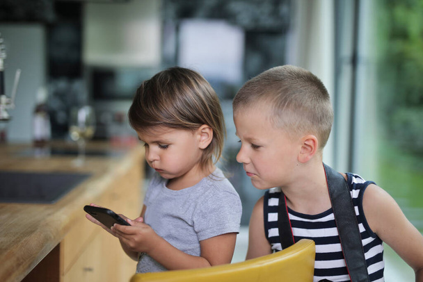 πορτρέτο δύο παιδιών στο σπίτι με smartphone - Φωτογραφία, εικόνα