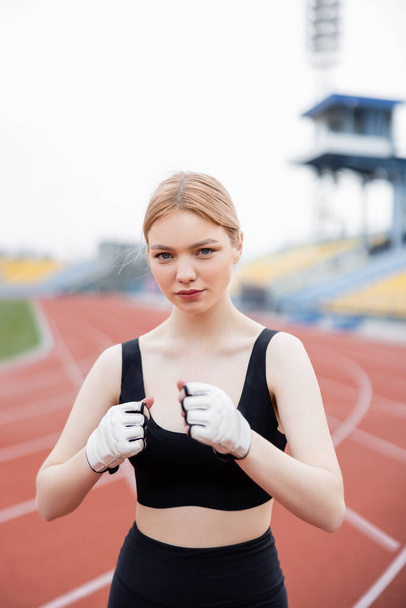 Sportliche Frau in Sport-BH und Fitness-Handschuhen beim Training im Stadion - Foto, Bild
