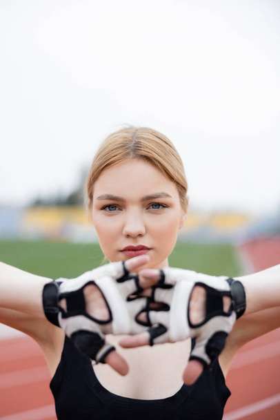 young sportswoman in fitness gloves warming up on blurred foreground - Foto, Imagen