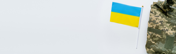 Top view of ukrainian flag near military uniform on white background, banner  - Photo, image