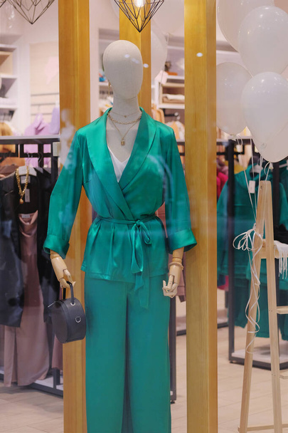 Schaufensterpuppen im großen Einkaufsladen. Schaufensterpuppe in grüner Freizeitkleidung steht in einem Bekleidungsgeschäft. - Foto, Bild