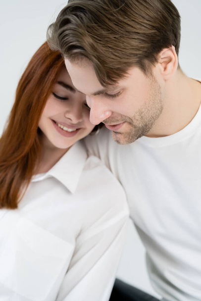 Young man looking away near blurred girlfriend in shirt isolated on white  - Valokuva, kuva