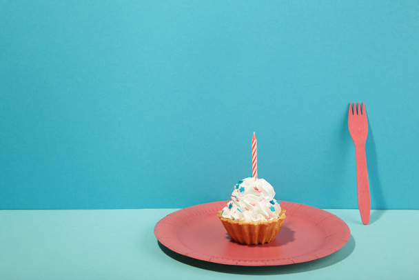 Delicious birthday cupcake with candle on pink plate on blue background. Top view - Φωτογραφία, εικόνα