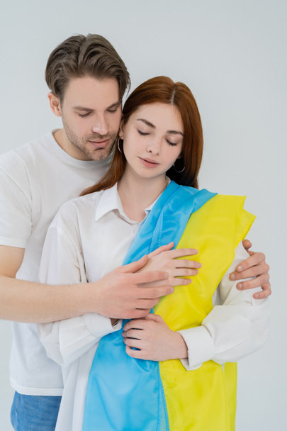 Young man hugging girlfriend with ukrainian flag isolated on white  - Fotoğraf, Görsel