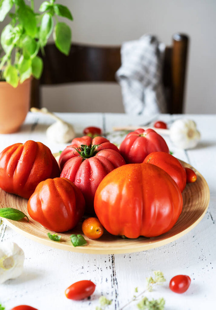 помідори на тарілці та білий дерев'яний фон з часником та стільцем
 - Фото, зображення