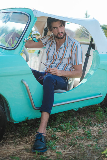 Ragazzo bruno italiano posa vicino a un'auto d'epoca Autobianchi Bianchina Spiaggina. Foto di alta qualità - Foto, immagini