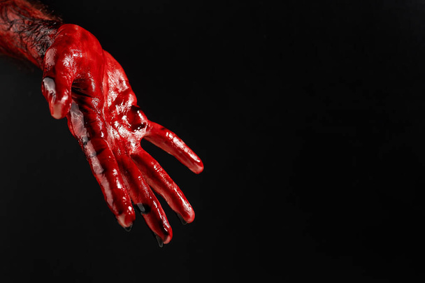 Close-up of a male hand stained with blood on a black background.  - Foto, Imagem