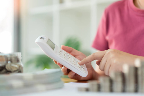 Conceito de poupança a mulher em um top vermelho calculando despesa mensal e renda usando a calculadora. - Foto, Imagem