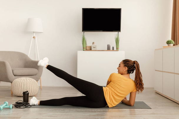Black Female Doing Side Leg erhöht Liegetraining zu Hause - Foto, Bild