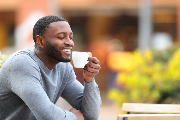 Happy man with black skin drinking coffee smiling in a bar terrace - Foto, Imagem