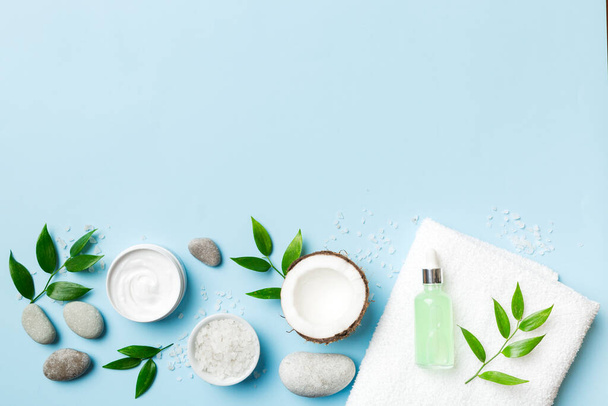 Coconut with jars of coconut oil and cosmetic cream on colored background. Top view. Free space for your text. Natural spa coconut cosmetics and organic treatment concept Coconut Spa composition. - Photo, Image
