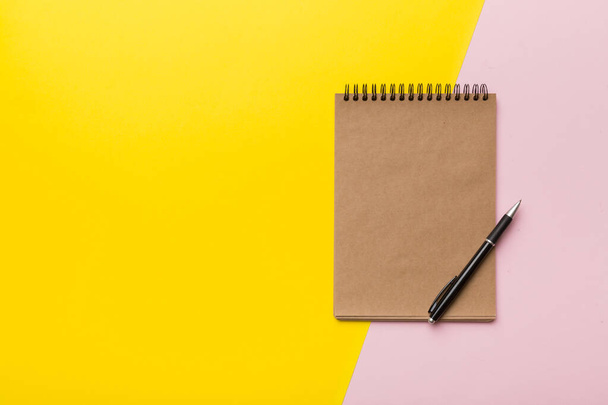 school bruin notebook op een gekleurde achtergrond, spiraalvormige ambachtelijke notitieblok op een tafel. - Foto, afbeelding