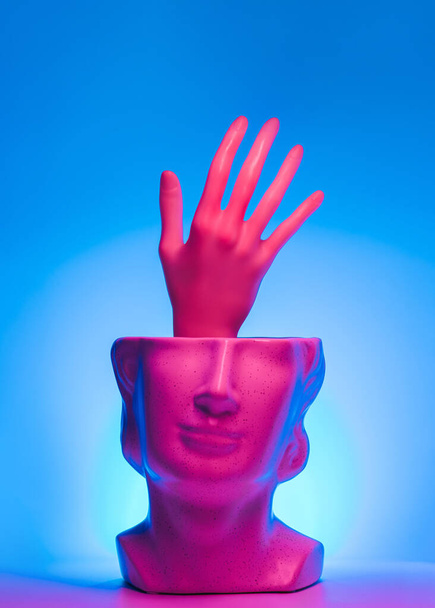 Käsi ojentaa patsas pään ja magenta sinivihreä led-valot. Neon, auta surrealistinen käsite. - Valokuva, kuva