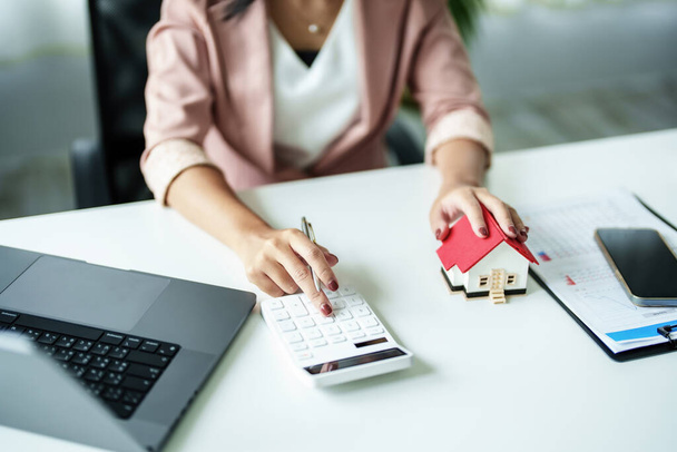 Imprenditori, imprenditori, commercialisti, agenti immobiliari, Una giovane donna utilizza una calcolatrice per calcolare il suo bilancio di casa per valutare i rischi di investire nel settore immobiliare. - Foto, immagini