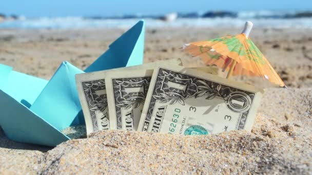 Blue small paper boat, half three dollar paper bills and paper cocktail umbrella - Footage, Video