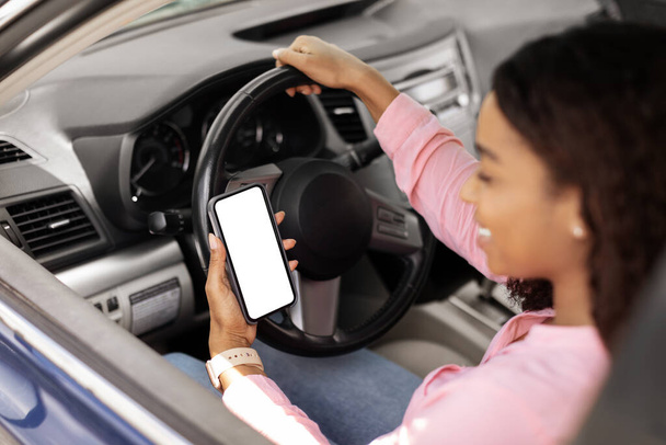 Mujer negra feliz usando teléfono inteligente con pantalla vacía coche de conducción - Foto, imagen