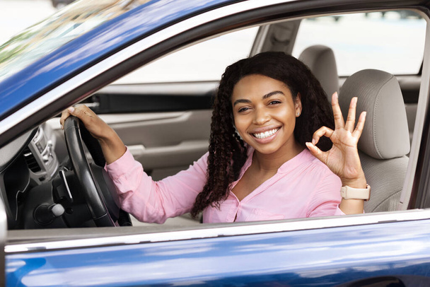 Heureuse femme noire assise dans la voiture montrant un geste correct - Photo, image