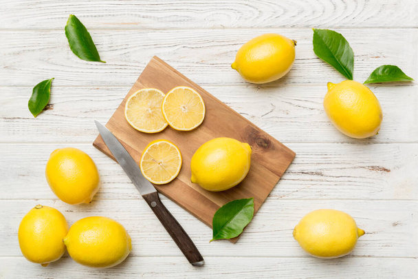 Top view with copy space for fresh and ripe lemons on cutting board. Healthy food background. Elegant background of lemon and lemon slices with squeezer and knife colored background. - Valokuva, kuva