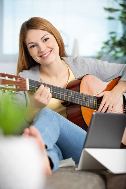 women playing guitar in the living room at home - 写真・画像