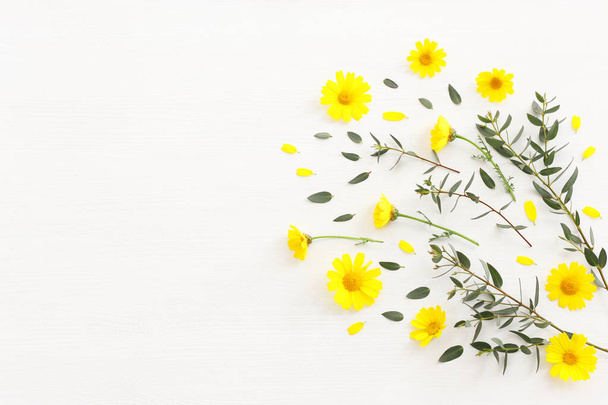 Top view image of yellow chrysanthemum field flowers composition over wooden white background. Flat lay - Zdjęcie, obraz