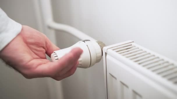 Man hand regulates temperature knob of heating radiator to reduce heating costs. - Footage, Video