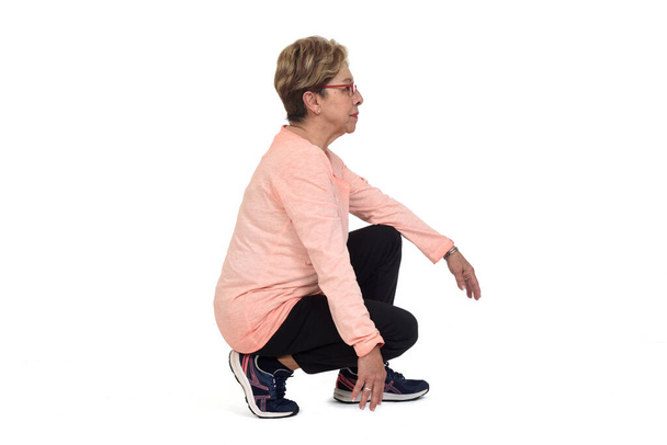 side view of a senior woman squatting on white backgrond - Foto, Imagen