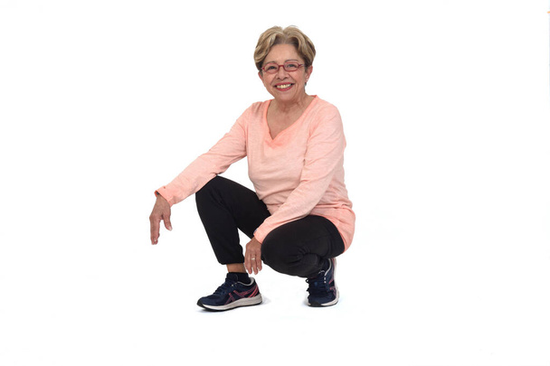front view of a happy senior woman squatting on white backgrond - Foto, Imagen