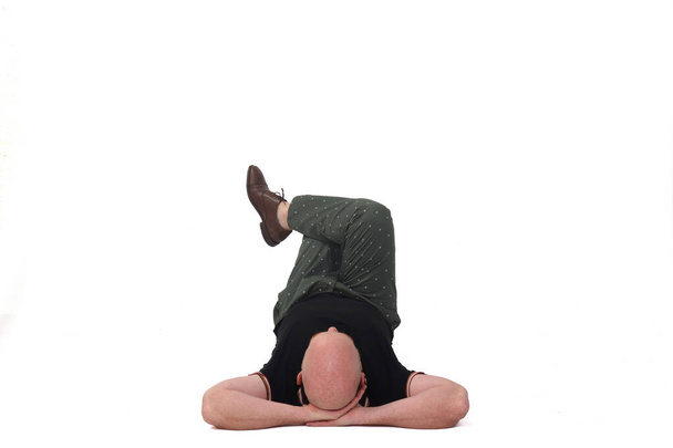 uomo sdraiato sul pavimento rilassato con le mani dietro il collo e le gambe incrociate su sfondo bianco - Foto, immagini