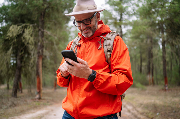 Egy férfi okos telefont használ az erdőben.. - Fotó, kép