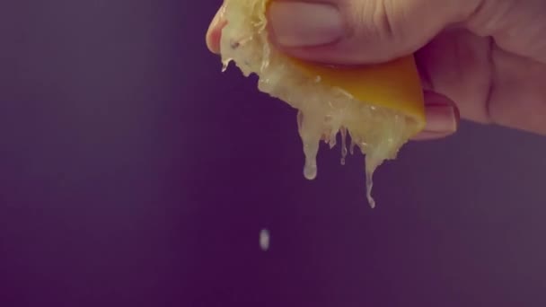 Hand squeezing half of lemon on black background. Hand squeeze lime with lime drop. Pressing and squashing lemon juice on hand in studio 4K video footage. Represent sour and refreshing drink menu. - Footage, Video