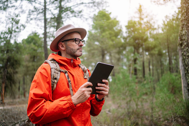Man met een tablet in het bos. - Foto, afbeelding