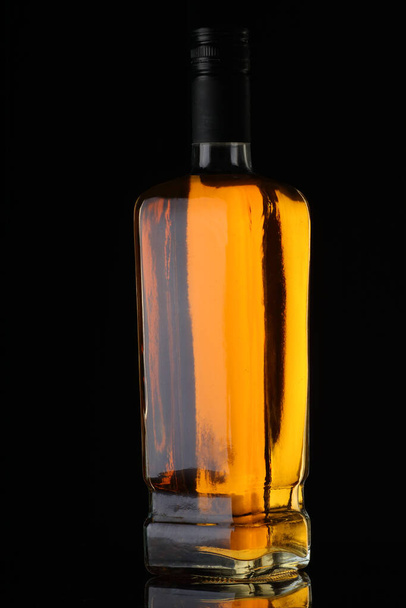 full whiskey bottle on black background with reflection - Foto, Imagen