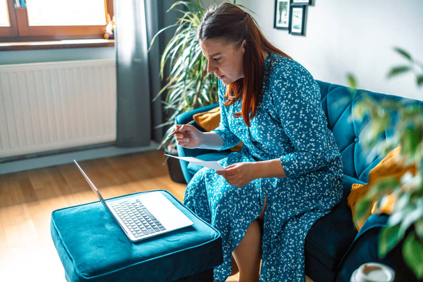 piękna poważna kobieta za pomocą laptopa płacąc rachunki online i zarządzania budżetem domu - Zdjęcie, obraz