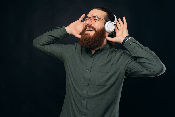 Człowiek z brodą dobrze się bawi słuchając muzycznych słuchawek.. - Zdjęcie, obraz