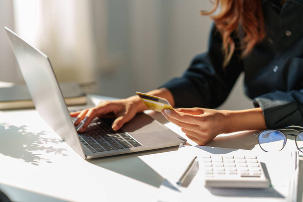 Vrouw met behulp van shopping website via laptop computer en betaling met creditcard. - Foto, afbeelding