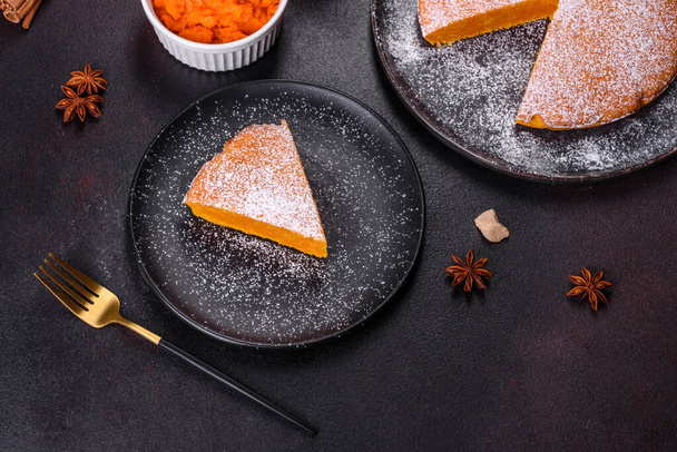 Pumpkin pie with whipped cream and cinnamon on a dark background, top view - Valokuva, kuva