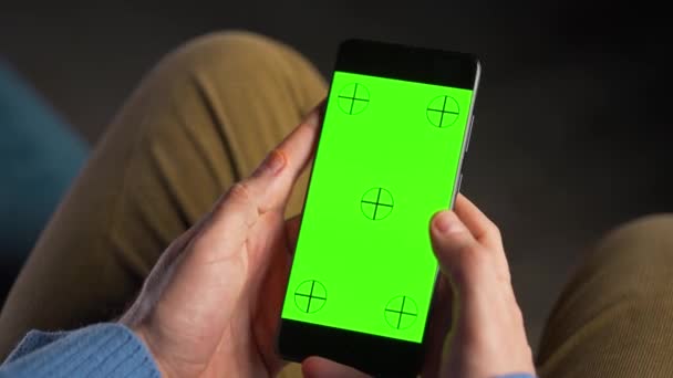 Человек, использующий смартфон с зеленым макетом экрана в вертикальном режиме. Человек просматривает Интернет, смотрит контент, видео. - Кадры, видео