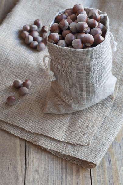 Hazelnuts in a cotton bag on a wooden table. - Foto, Imagem