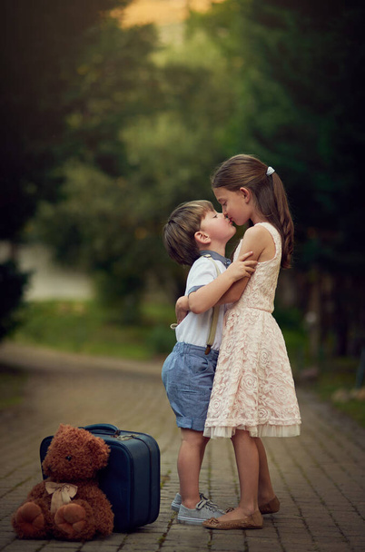 Rodzina oznacza miłość na zawsze. Strzał cute little girl całuje jej młodszego brata podczas zabawy na zewnątrz. - Zdjęcie, obraz
