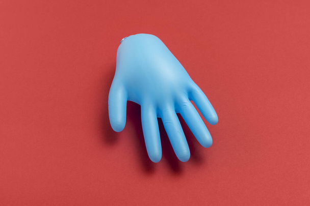 Opgeblazen rubberen handschoen op een rode achtergrond. Reinigingsconcept. - Foto, afbeelding