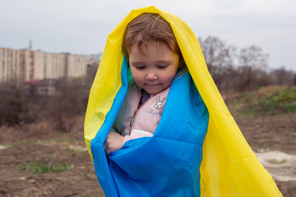Belle petite fille avec un drapeau de l'Ukraine dans le contexte d'une ville et un lac dans une ville ukrainienne. Portrait d'une petite fille patriotique avec le drapeau de l'Ukraine. - Photo, image