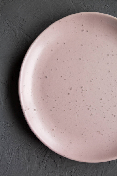 Placa de cerámica rosa vacía sobre un fondo gris, vista superior. - Foto, Imagen