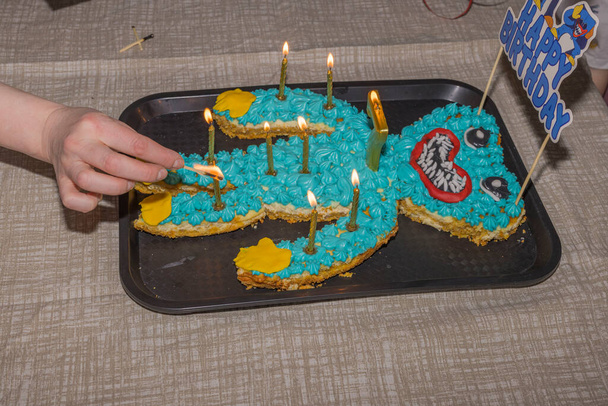Az ember keze gyertyát gyújt egy tortában, hogy megünnepelje a gyerek születésnapját. Svédország.  - Fotó, kép