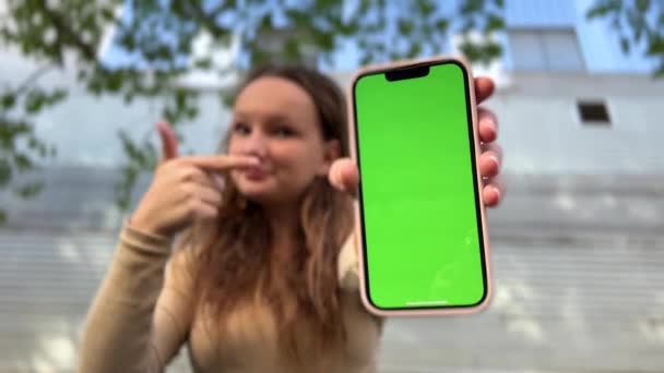 Teenage dívka s volnými vlasy hnědé vlasy hnědé vlasy tance s telefonem raduje na obrazovce kulhání zelené obrazovce béžové pozadí - Záběry, video