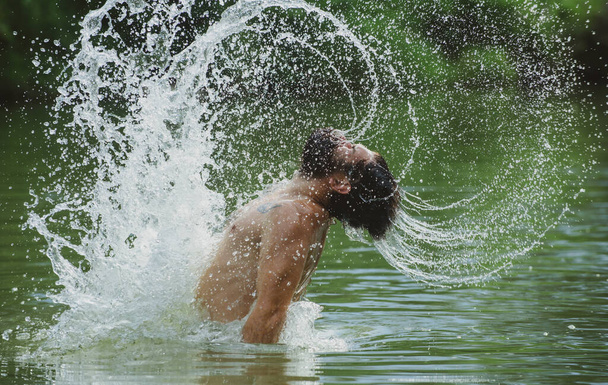 Sexy bearded man with wet hair and beard swimming in water and drops. Gay splashing water by his wet hair and beard on face having fun. Feel the freedom. - Foto, Imagem