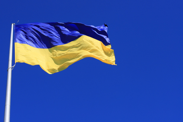 Die Flagge der Ukraine flattert am blauen Himmel. Große gelb-blaue ukrainische Nationalflagge, Stadt Kiew, Ukraine. Symbol des ukrainischen Sieges im Krieg gegen die russische Aggression - Foto, Bild