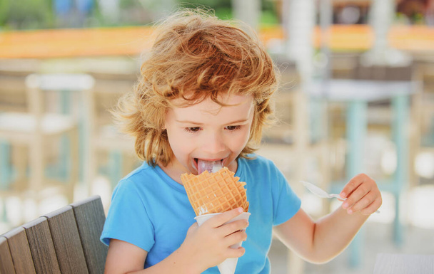 Cute child licking big icecream in waffles cone. Kids eating ice cream in cafe. - Foto, afbeelding