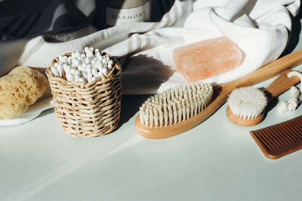 Natural cosmetics, soap, wooden brushes, ear cleaning sticks, comb and natural sponge on light blue table. Beauty, spa and wellness. Zero waste concept. Copy space - 写真・画像