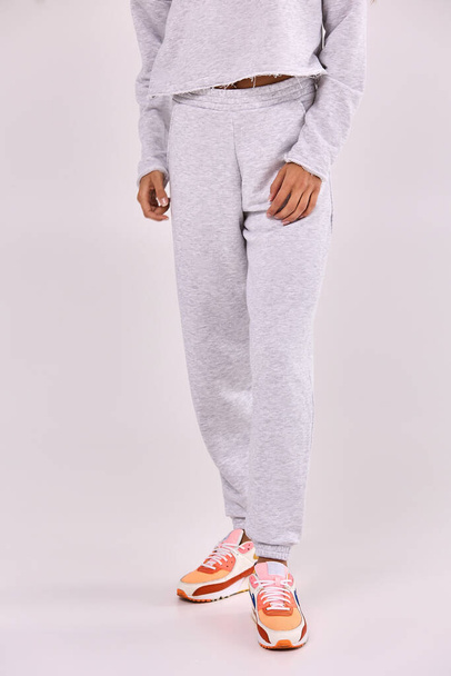 A young girl in grey sweatpants on a white background - Foto, imagen